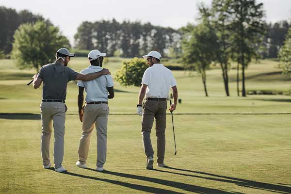 Three men walking on a golf course, engaging in a fun social golf event in San Antonio.
