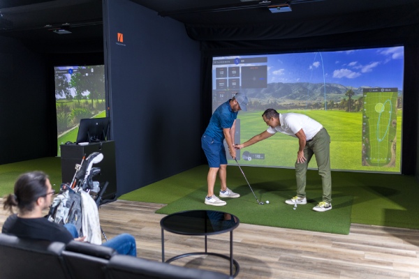 A man and woman enjoying a golf lesson on a simulator in an indoor setting in San Antonio.