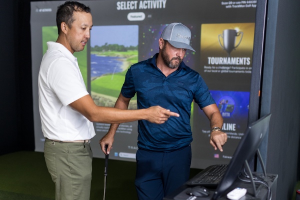 Two men reviewing trackman technology while using a golf simulator during an indoor lesson in San Antonio.