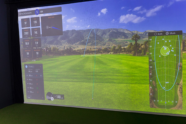 A golf simulator featuring a lush green field and a golf ball, showcasing advancements in golf training technology.