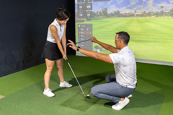 A man and woman engage in a golf simulator game, highlighting expert advice on golf courses in Texas.