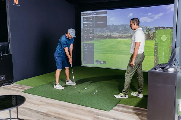 Two men enjoying a round of golf on a simulator in a San Antonio room designed for indoor golfing experiences.