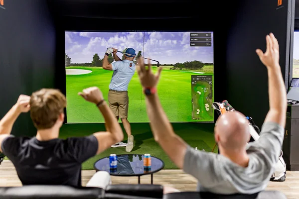 Two men playing golf in a video game simulator in a room at Golf Simulator San Antonio.