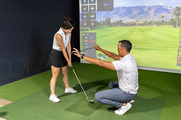 A man and woman engage in a winter golf simulation, playing together on a high-tech golf simulator.