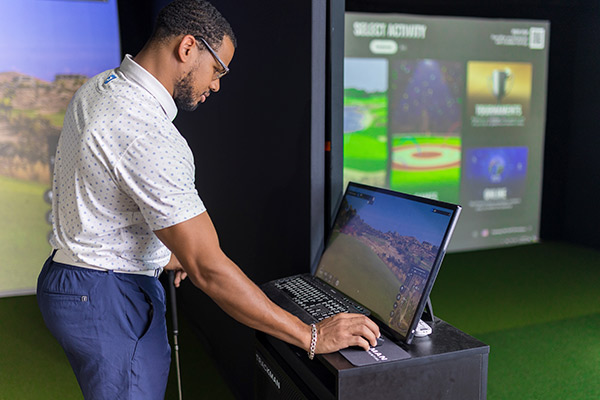 Man reviewing laptop with trackman for golf technology 
