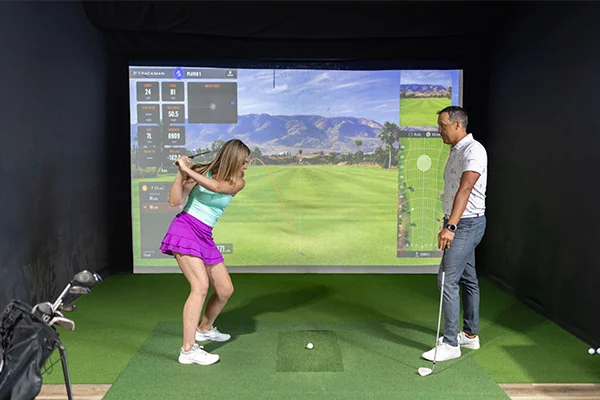 A man and woman engaged in a golf simulator game, highlighted in the 2026 guide for indoor golf in San Antonio.