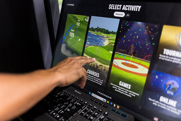Individual engaged in a golf simulation on a computer, exploring options between golf simulator and Topgolf in San Antonio.