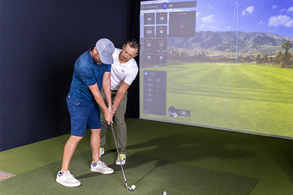 Two men shaking hands in a golf room, symbolizing a welcoming atmosphere for first-time golf lesson participants.