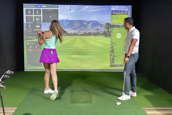 A man and woman engaged in the Fairway golf simulator session, promoting 'Women in Golf: Growing the San Antonio Community.'