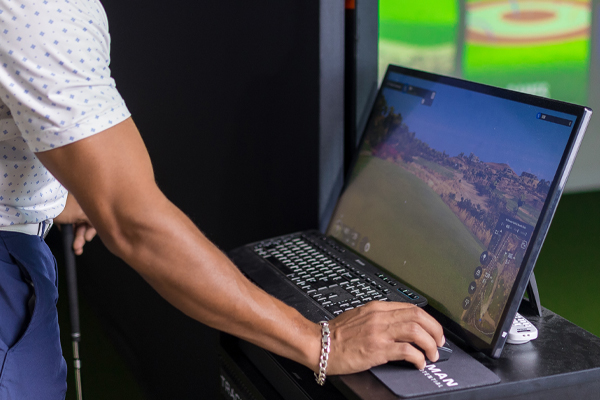 Person working on monitor for trackman golf analysis