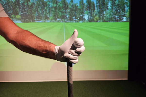 A golfer preparing to tee off indoors at a virtual golf simulator on a sunny day
