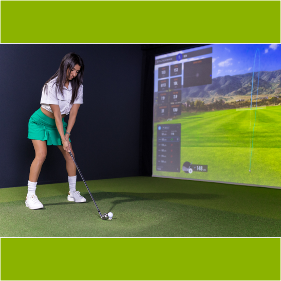 A woman in a white top and green skirt prepares to hit a golf ball in a virtual golf simulator setting.