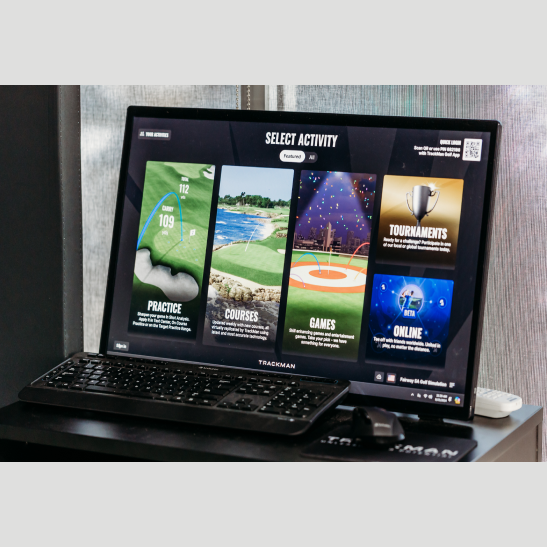 A computer monitor displaying a golf simulation interface with options for practice, courses, games, tournaments, and online activities.